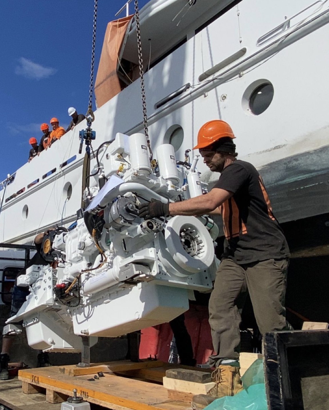 Technician installing marine engine alongside a vessel at port