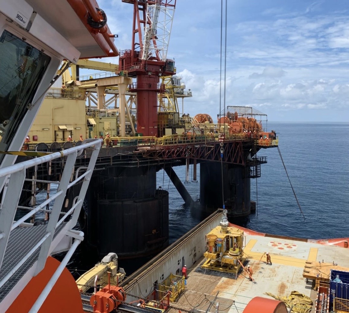 Offshore oil platform with crane operations and supply vessel