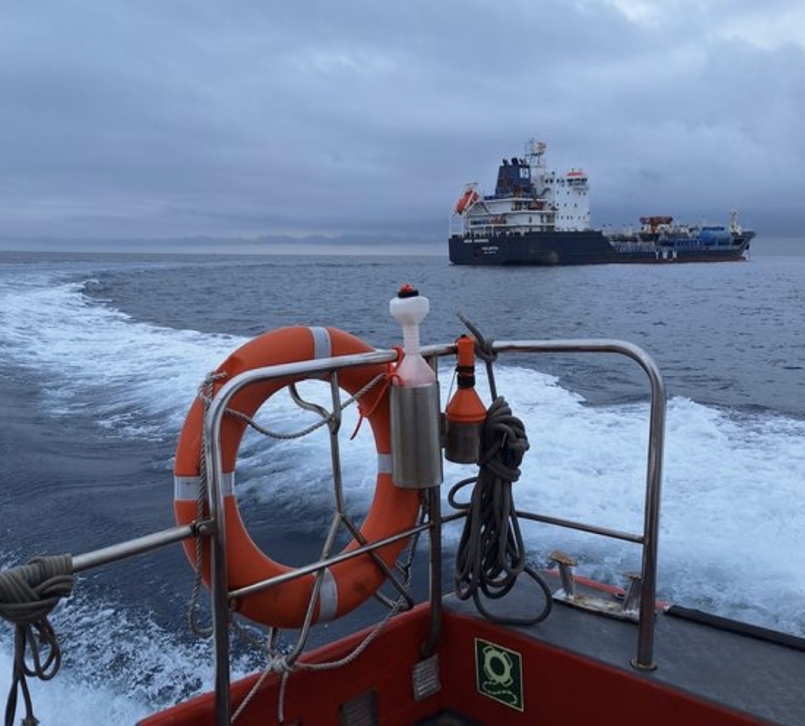 Safety boat with life ring approaching cargo ship at sea