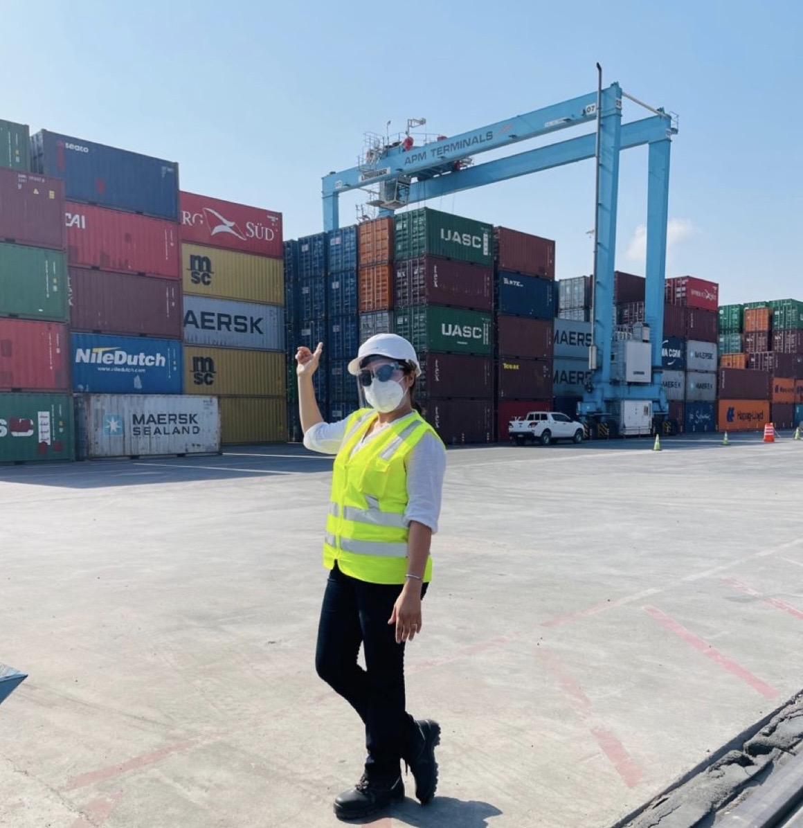 Worker in safety vest at container terminal with gantry crane