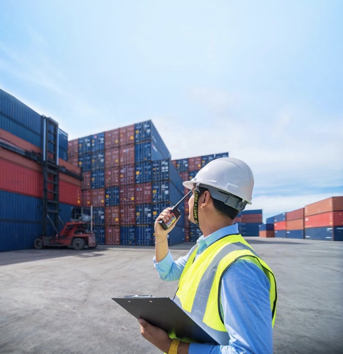 Logistics coordinator with clipboard and radio at container yard